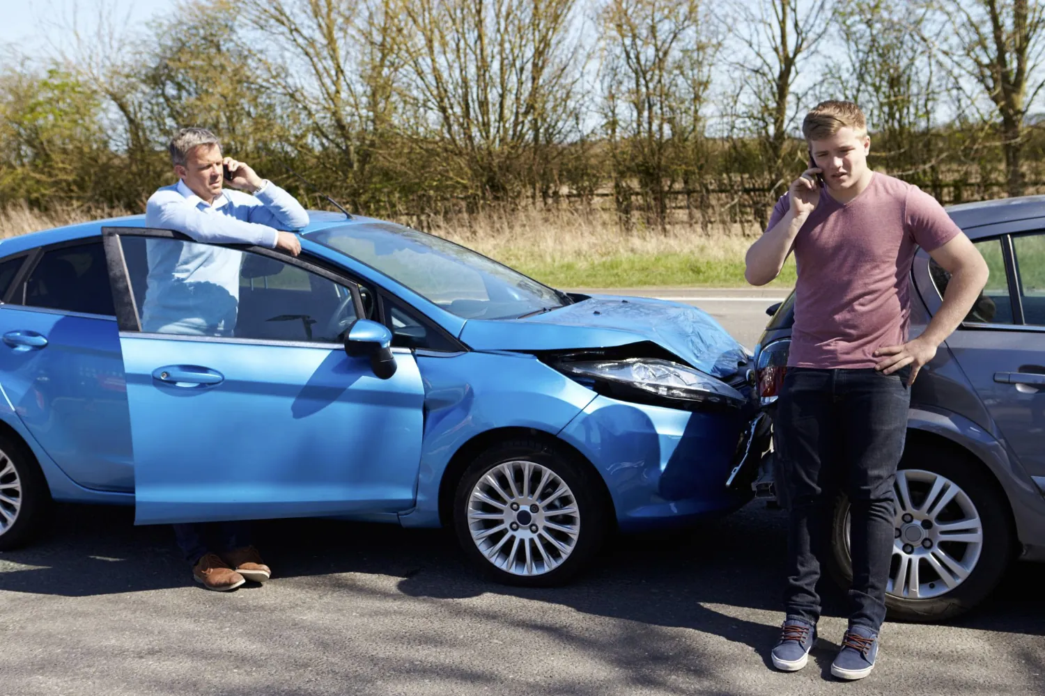 Zwei Unfallbeteiligte nach einem Auffahrunfall in Frankfurt am Main dokumentieren den Schaden an einem blauen PKW per Telefon. Ein unabhängiger Kfz-Sachverständiger ist hier entscheidend, um die „Bagatellschaden-Falle“ der Versicherungen zu vermeiden und versteckte Mängel an PDC-Sensoren oder dem Prallelement rechtssicher für die Schadensabwicklung zu erfassen.