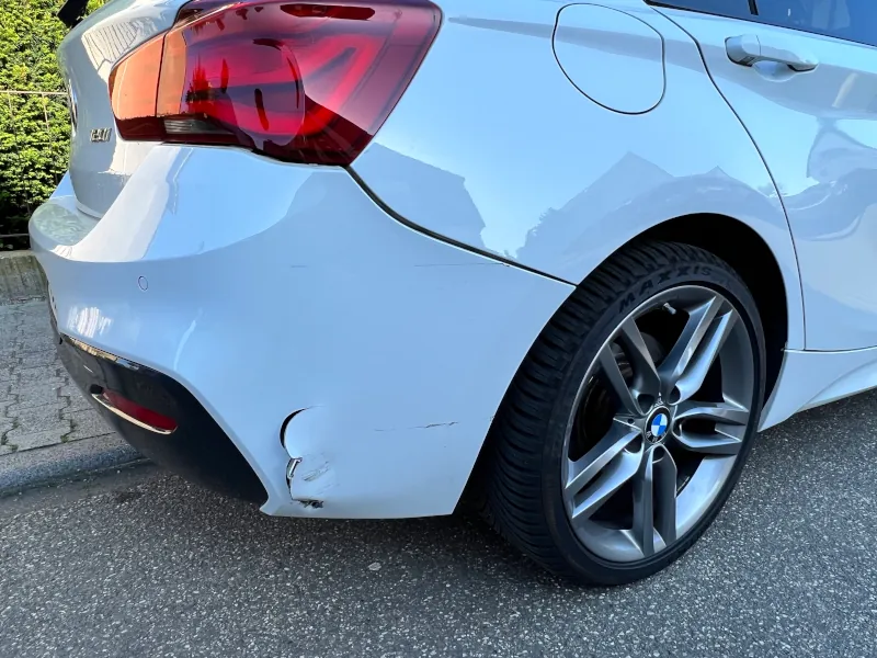 Heckschaden an einem weißen BMW 120i M Sport in Frankfurt am Main – Deutliche Rissbildung im Stoßfänger durch Unfallereignis